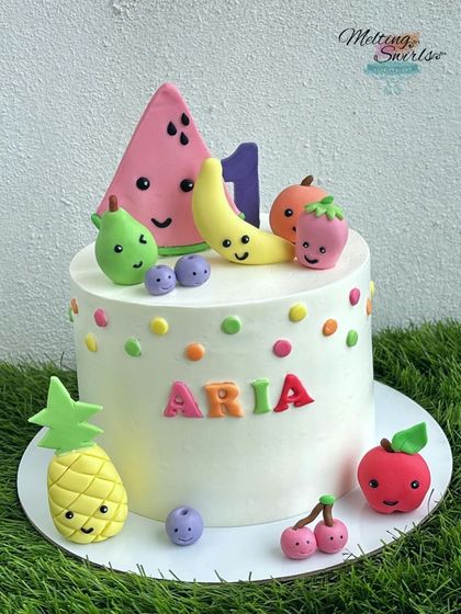 A "tutti frutti" themed cake for a first birthday. This simple white cake is decorated with colorful polkadots and adorable, handmade fondant fruits with smiley faces.