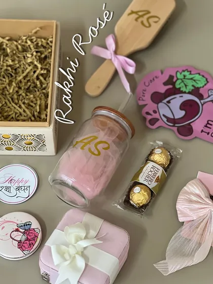 Our 'Rakhi Rosé' hamper is a collection of pretty, personalized items for your sister. It includes a glass tumbler, a hairbrush, a jewelry box, and Ferrero Rocher chocolates, all in lovely shades of pink.