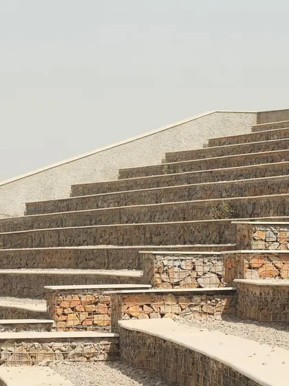 The tiered seating of the amphitheatre follows the natural contours of the hill. The combination of rough stone-filled gabions and smooth concrete tops creates a textural contrast that is both rustic and refined.