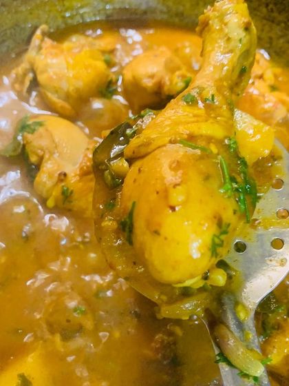 A spoonful of the chicken masala curry, showing a tender drumstick.