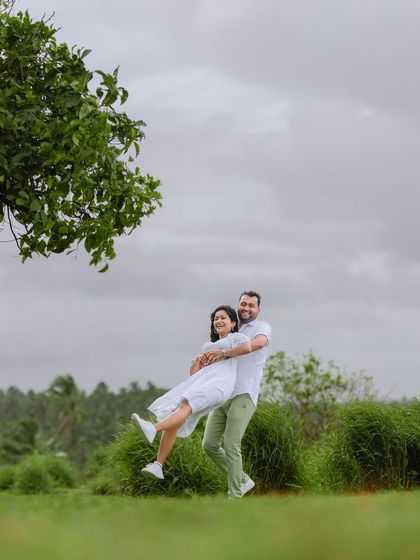 Another angle of a joyful lift, showing the happiness and trust between the couple. The cloudy sky creates a soft, flattering light.