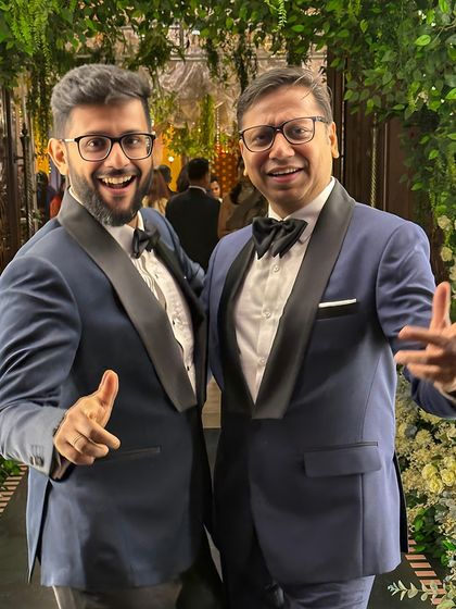Two gentlemen looking sharp in our classic blue tuxedos with black satin lapels. A timeless choice for any formal event, tailored to perfection for a flawless silhouette.