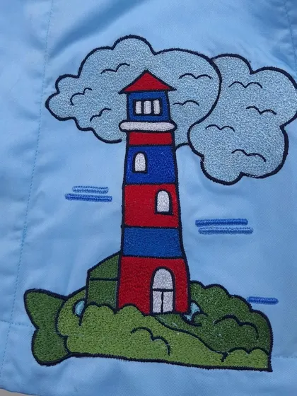 This is a close-up of a lighthouse embroidery from a boat-themed saya kurta I made for a child's first birthday.