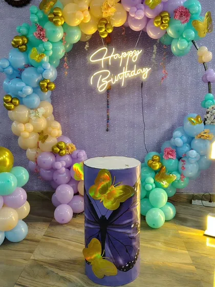 The complete setup for a first birthday with a butterfly theme, showing the circular balloon frame and custom decor elements.