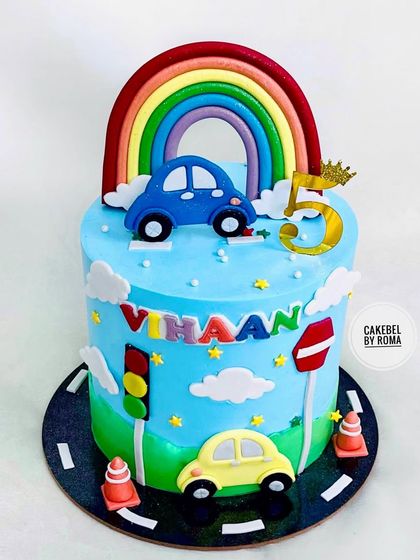 A cute car-themed cake for Vihaan's 5th birthday. This design features a road, traffic signals, and a bright rainbow arching over the sky.