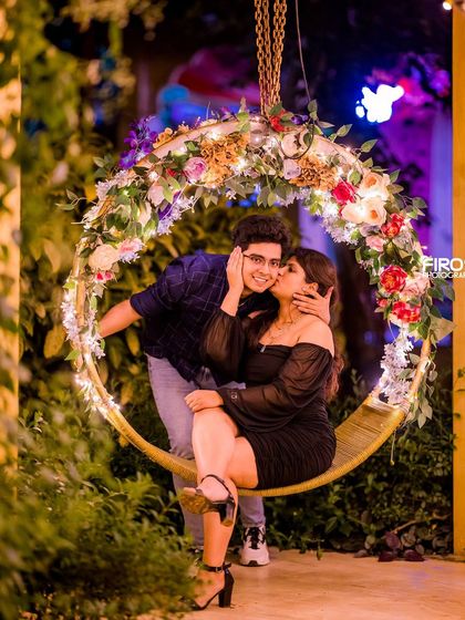 A sweet kiss on the cheek on our floral swing at night, a perfect candid-style moment.