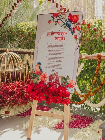 The welcome sign for the 'Gulmohar Bagh' event, adorned with fresh red flowers.