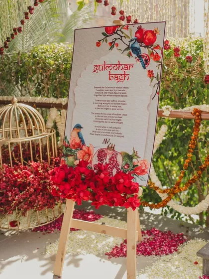 The welcome sign for the 'Gulmohar Bagh' event, adorned with fresh red flowers.