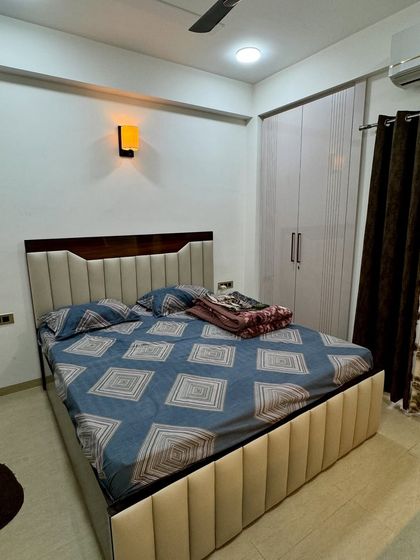 Another angle of the bedroom, showing the channel-tufted upholstered bed base and the simple, elegant wardrobe design.