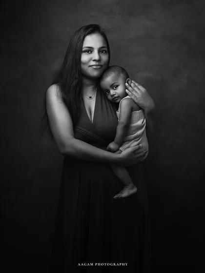 A mother and her baby, captured in classic black and white. The lighting highlights their expressions and the tender way she holds her child, creating a powerful, emotive portrait.