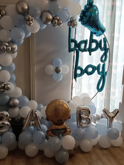 A sweet and simple 'Baby Boy' welcome home decoration. This setup includes a balloon half-arch in blue, white, and silver, along with 'BABY' foil letters, 'BABY' blocks, and other themed foil balloons.