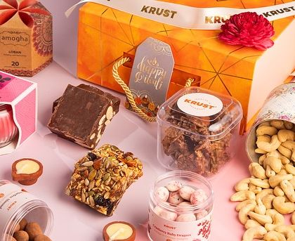 A beautiful flat lay of one of our Diwali gift boxes, featuring cashews, granola bars, chocolate fudge, and a scented candle. It's a gift for all the senses.