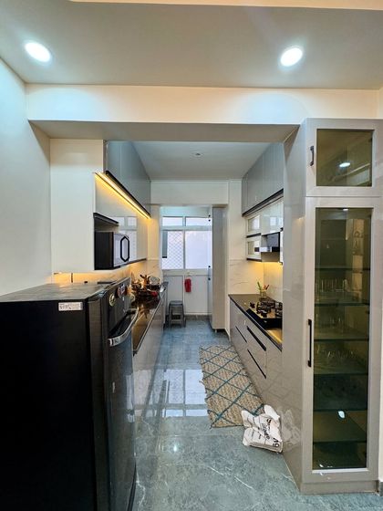 A full view of a completed galley kitchen project in Amrapali Princly Estate. The design uses light-colored cabinets to make the space feel bigger and brighter.