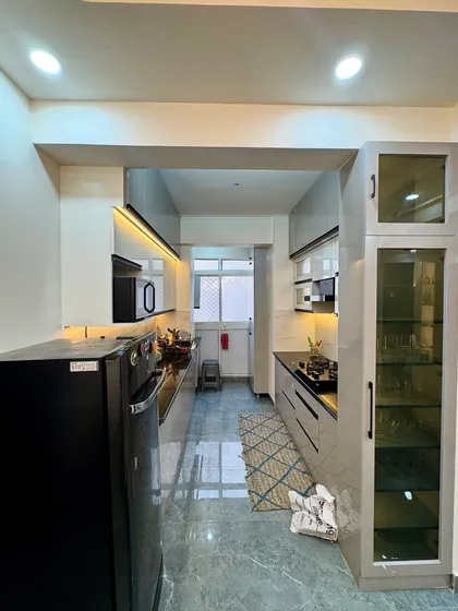 A full view of a completed galley kitchen project in Amrapali Princly Estate. The design uses light-colored cabinets to make the space feel bigger and brighter.
