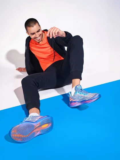 A joyful and candid-style shot for a shoe campaign. The model's smile and relaxed posture, combined with a clear view of the shoe's sole, create an approachable and appealing product image.