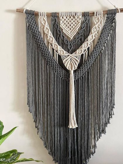A full view of the grey and off-white macrame tapestry. I love how the natural white tassel hangs down in the center. This piece brings a modern and classy boho feel to any space.