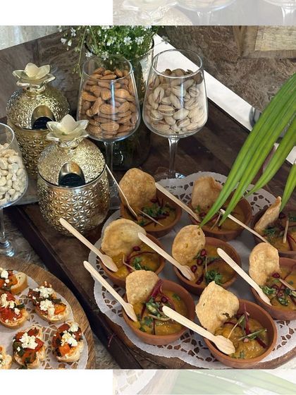 A beautiful spread of appetizers including bruschetta and chaat, alongside glasses of nuts, perfect for guests to nibble on.