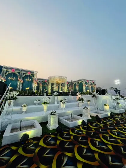 A full wide shot of the teal palace stage, capturing the entire structure against the evening sky. This view emphasizes the sheer size and grandeur of the custom-built reception backdrop.
