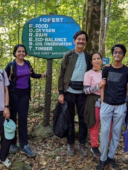 A family posing next to a forest conservation sign, reminding us to protect these beautiful places.