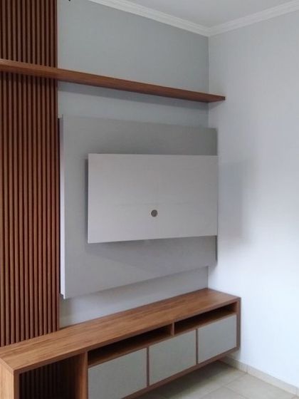 A compact and stylish TV unit with a mix of wood and grey finishes. The vertical wood panelling adds texture and warmth, while the asymmetrical shelving provides space for decor and media devices.