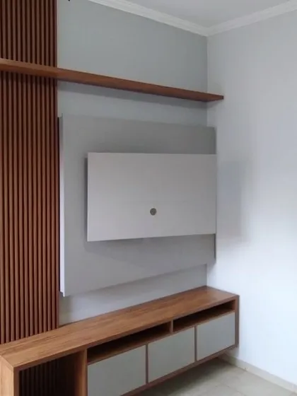 This TV unit features a combination of wood-fluted paneling and a simple grey back panel. The design includes an open shelf and a low console with drawers, offering both display space and concealed storage.
