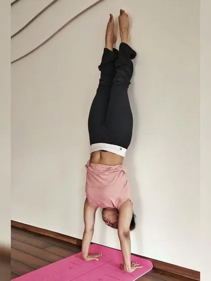 Finding stability and alignment in a wall-assisted handstand. This practice is fundamental for developing the core engagement and body awareness required for freestanding inversions.
