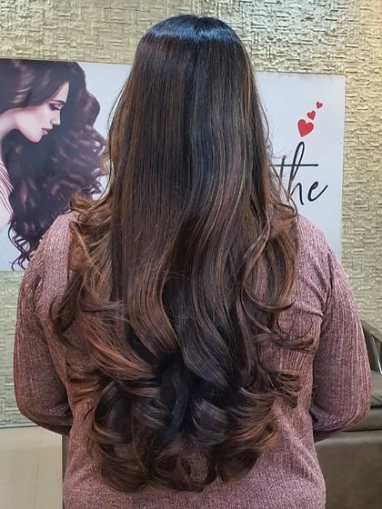 The back view of a stunning hair colour and style. The long layers are enhanced by subtle highlights, and the voluminous curls give the hair a glamorous, healthy appearance.