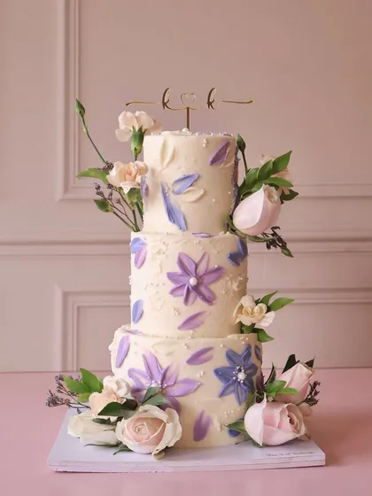 For the big days, we love creating something truly special. This three-tiered wedding cake features delicate, hand-painted watercolor flowers in shades of lavender and is adorned with fresh roses, making it a beautiful centerpiece for a memorable celebration.