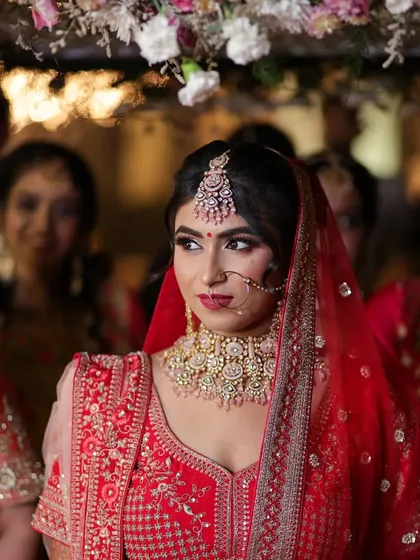 A beautiful shot of the bride entering under the phoolon ki chadar. Her makeup looks flawless and radiant.