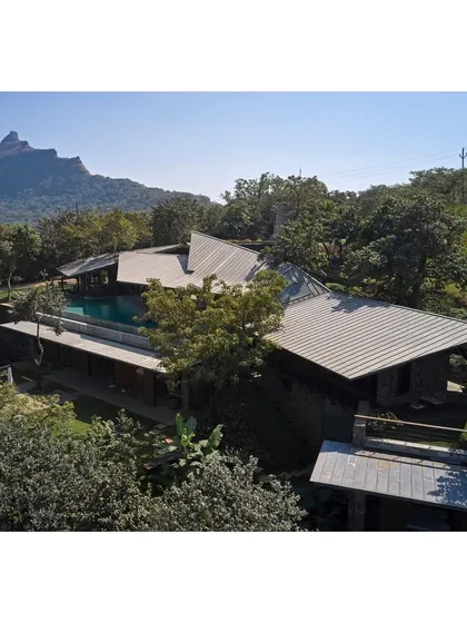 An aerial view of the Lateral Verandah House shows how the structure is nestled into the lush green hillside, its form dictated by the natural contours of the land.