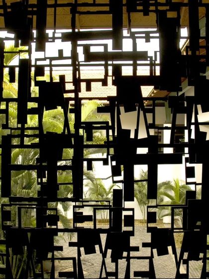 A close-up view of the abstract, patterned jaali at the LMW Headquarters. The screen's design, made from scrap metal, creates a complex play of solid and void, casting intricate shadows while providing ventilation.