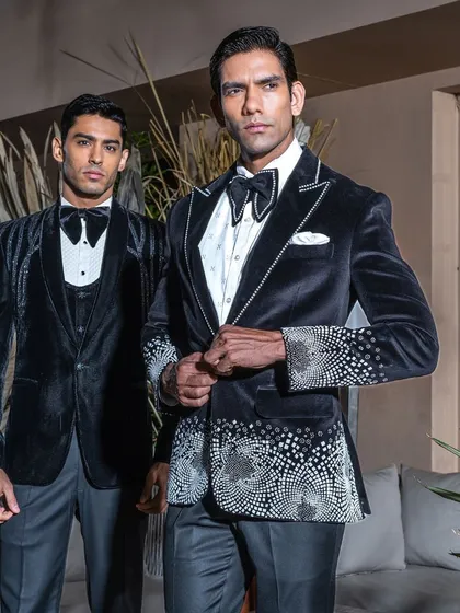 We craft wedding tuxedos that are designed to be as memorable as the occasion itself. This image showcases two of our signature velvet tuxedos, featuring intricate crystal work and a modern silhouette, perfect for the groom who seeks distinction and elegance.