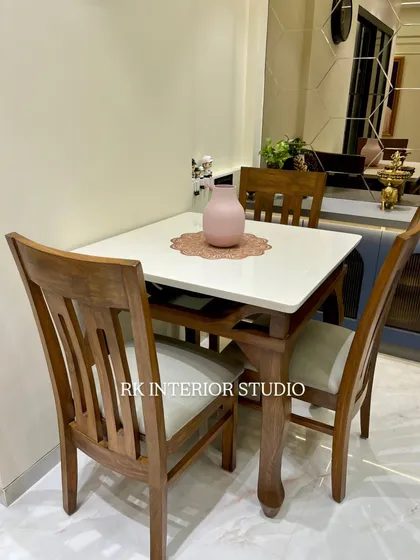 A classic four-seater dining table with a marble top and sturdy wooden chairs. This setup is perfect for a family, providing a comfortable and durable space for daily meals.