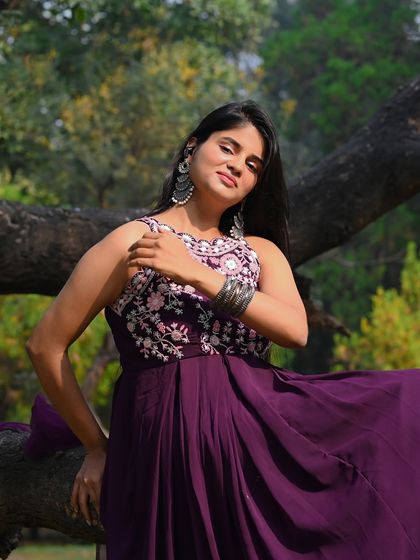 A serene and artistic shot of a model in a beautiful purple gown, posing with a tree in a park. This is a great example of blending fashion with nature.