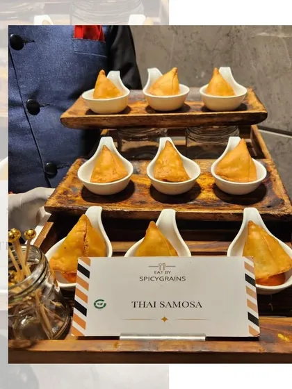 A fusion delight: Thai Samosas. These crispy pastries are filled with a fragrant Thai-inspired vegetable mix, served in individual tasting spoons for an elegant presentation.