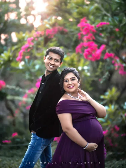A stylish back-to-back pose that feels both playful and romantic, set against a backdrop of vibrant pink flowers.