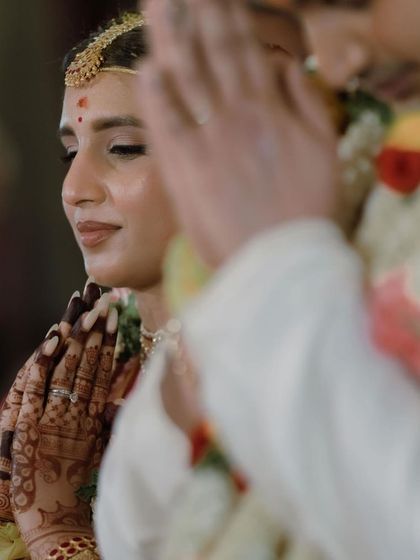 A candid moment from a wedding ceremony, capturing the bride's serene expression and her beautiful mehendi.