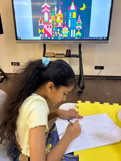The process is just as important as the final piece. Here, a student carefully sketches her castle design before painting, learning about planning and composition in art.