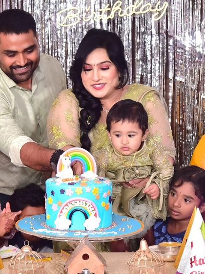 A cheerful rainbow-themed cake for a first birthday party. The family gathers around to celebrate this colorful milestone, creating a memory as sweet as the cake itself.