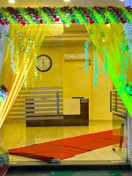 A simple flower decoration for a party hall entrance. The doorway is draped with yellow curtains and accented with small floral bouquets.