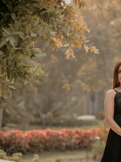 A simple and elegant solo maternity portrait in a black gown, showing how beautifully a darker dress can stand out against the soft greens and reds of a garden.