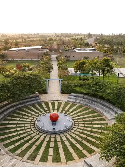 An aerial view of the stone amphitheater at the H.N. Science Center, a space designed for community gathering and learning. The design integrates with the landscape, using local stone and grass to create a functional yet organic public space.