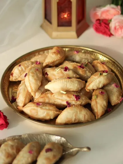 A platter of my freshly made Nutty Gujiyas, garnished with rose petals and ready to be shared.