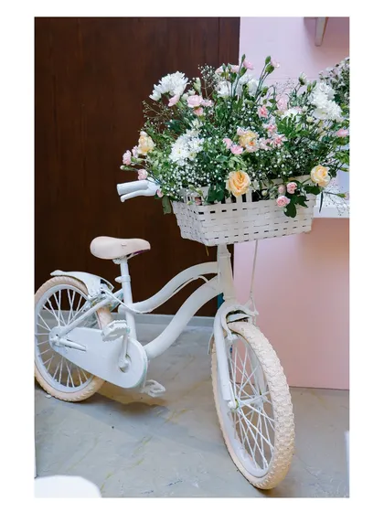 Another view of the charming bicycle prop, highlighting the lush arrangement of white and pink flowers. This kind of thoughtful prop styling helps build a cohesive and immersive theme.