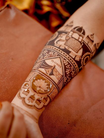 A close-up of the forearm, showing the intricate details of the elephant and dhol motifs. The negative space technique makes the figures stand out beautifully.