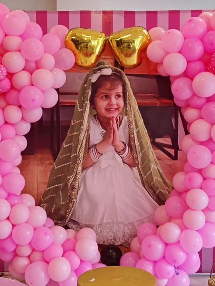 A close-up of a Minnie Mouse-themed party, showing a photo of the birthday girl framed by a heart-shaped balloon sculpture.