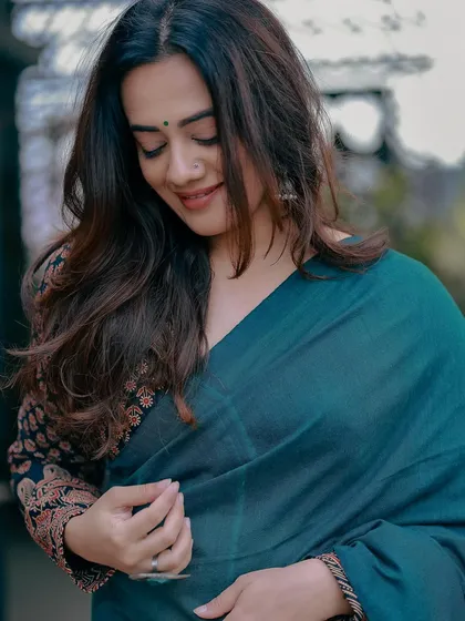 A soft, candid shot that highlights the texture and drape of the green saree.