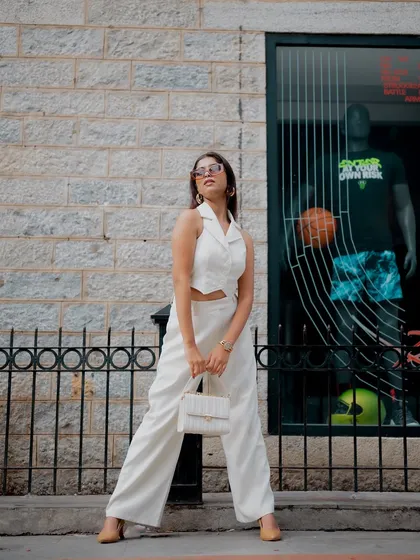 A full-length shot of a model in a chic white outfit, walking down a city street. This captures a natural, in-motion fashion moment.