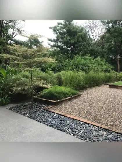 The different textures of the zen garden are highlighted in this view. The fine gravel, smooth river stones, and soft grass create a tactile and visually calming composition.