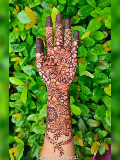 A full-coverage henna design from wrist to fingertips. This piece incorporates classic rose motifs, leafy vines, and geometric patterns for a rich and textured look.